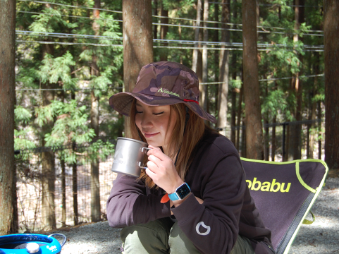 キャンプでコーヒーを飲む女性